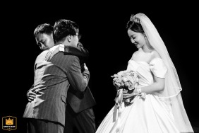   In Kaifeng, China, a father embraces the groom with emotion after giving his daughter away, symbolizing the joining of two families during the wedding ceremony.